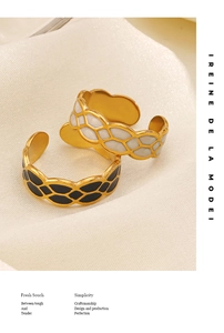 Detail of gold-plated open rings with black and white enamel honeycomb texture on silk