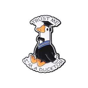 Cartoon enamel graduation duck pin with Trust Me I'm a Ducktor text on white background