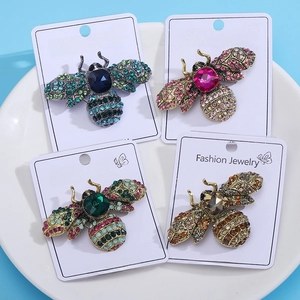 Macro view of four vintage crystal bee brooches in blue pink green and amber colors