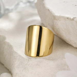 Detailed view of polished wide gold stainless steel ring on white natural stone base