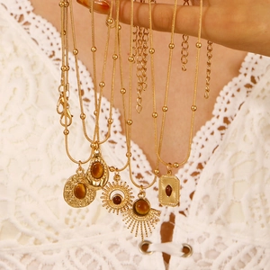 Detailed close-up of gold layered necklaces with diverse brown tiger eye stone pendants