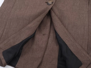Détail d'une veste marron texturée avec doublure noire et finitions de boutonnage