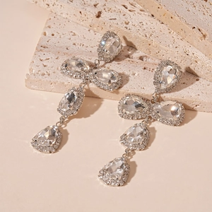 Macro shot of silver drop earrings with crystal tassels on textured stone surface