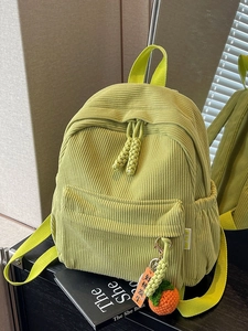 Light green corduroy backpack with vertical stripes and orange pumpkin charm on book