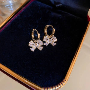 Detailed close-up of gold-plated bow earrings with sparkling cubic zirconia on blue velvet