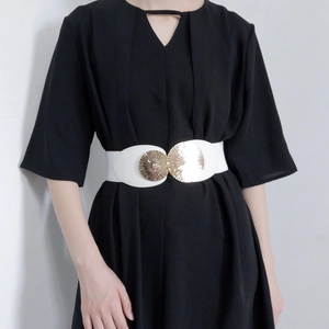 Detail of white elastic waist belt with double gold circular textured metal buckles on dress