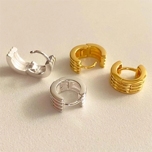Detailed close-up of 925 silver hoop earrings in gold and silver with textured stripes