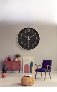 Modern black wall clock with rose gold numerals on a grey wall in a living room