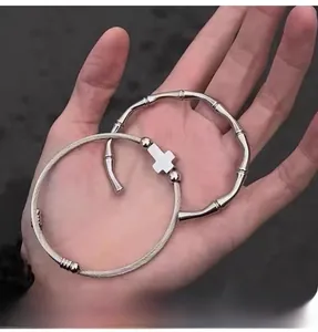 Detail showing stacked stainless steel cable cross bracelet and bamboo joint cuff