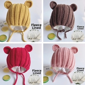 Close-up of fleece-lined baby knit hats with bear ears in yellow, brown, red, and pink