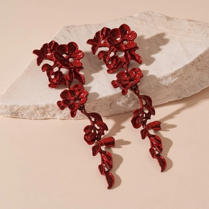 Close-up of dark red flower tassel earrings on white stone with vintage leaf details