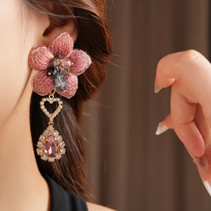 Détail d'une boucle d'oreille vintage avec fleur brodée rose et bijou en goutte d'eau