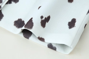 Gros plan sur l'imprimé vache et les coutures précises du tissu en maille blanche