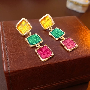 Gros plan détaillé de boucles d'oreilles rétro émaillées colorées sur un coffret en cuir