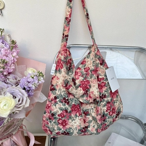 Floral canvas tote bag with red flowers and MISS label hanging on a transparent chair