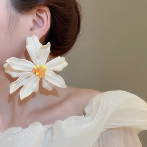 Close-up of white 3D acrylic flower earring with yellow stamen worn by a model