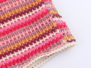 Close-up of colorful striped crochet fabric with white openwork lace trim detail
