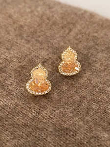 Macro detail of gold-plated Wu Lou earrings with amber stone and zircon inlay