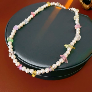 Detail of white pearls and multicolor crystal stone necklace on green jewelry pad