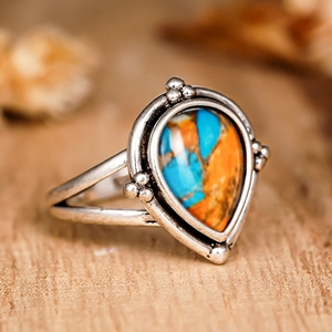 Gros plan d'une bague vintage en argent avec pierre goutte d'eau orange et bleue