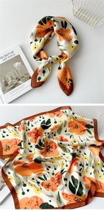 Detail of silk-like square scarf with orange floral prints and brown rolled edges