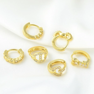 Collection of six elegant golden geometric huggie earrings with white zircon on silk
