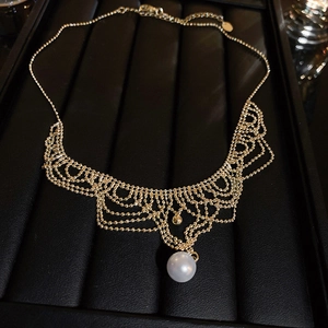 Macro detail of 24K gold-plated lace mesh chain necklace with a white pearl pendant
