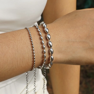 Close-up of three-piece silver stainless steel oval bean bead bracelets on a female model