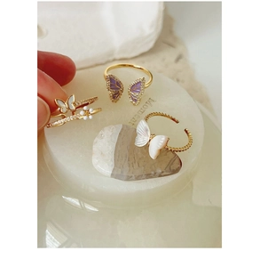 Detailed view of gold butterfly rings with pearls and sparkling shell accents