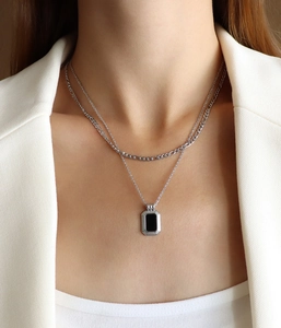 Detail view of double-layer silver chain necklace with a black rectangular pendant on model