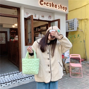 Detail of light green quilted floral bag paired with a beige sherpa jacket