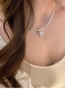 Detail of silver heart pendant necklace on model showcasing polished metal finish