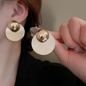 Detail of round gold mirror finish geometric stud earrings worn by a model
