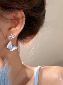 Close-up detail of ice-clear blue butterfly earrings with sparkling flower stud