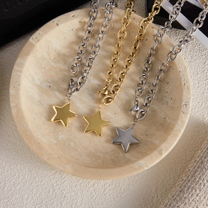 Detailed view of gold and silver star pendant necklaces in a marble bowl