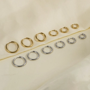Detailed set of polished gold and silver hoop earrings in various sizes on silk fabric
