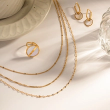Detail of layered gold texture necklaces and geometric earrings with light and shadow