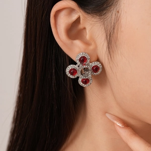 Luxury silver stud earrings with G logo red gemstones and crystal accents on model