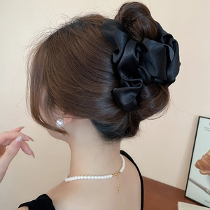Detail of a large black satin cloud hair scrunchie styled on a classic French ponytail