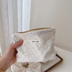 Detail of white floral lace embroidery on pouch with simple wish label and matching scrunchie