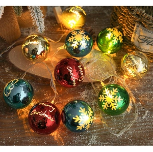 Close-up of LED Christmas string lights with colorful Merry Christmas globes on snow