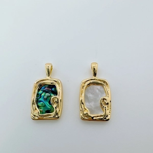 Close-up of 18K gold-plated abalone and white shell pendants with wavy metal texture