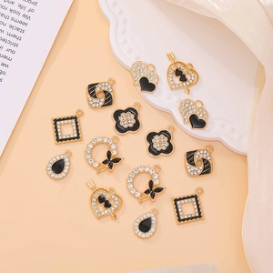 Vue à plat de 14 breloques dorées avec émail noir et strass pour la création de bijoux