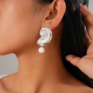 Detailed view of silver nautical conch shell earring with a white pearl on model