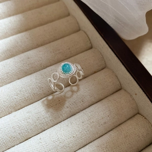 Detail of turquoise stone ring with woven silver band and adjustable open design