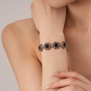 Close-up of rose gold flower bracelet featuring blue crystals and sparkling rhinestones