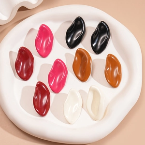 Minimalist irregular oval drop earrings in five colors displayed on a white shell tray