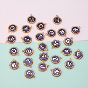 Detailed flat lay of black enamel round letter charms with gold-plated metal borders