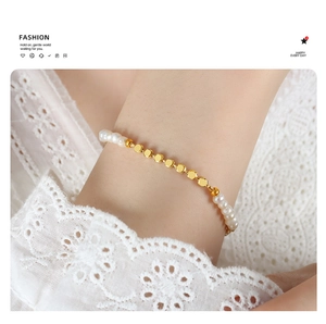 Close-up of elegant freshwater pearl and gold bead chain bracelet on a lace sleeve