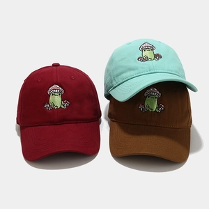 Detail of embroidered green frog and red mushroom icons on cotton baseball caps